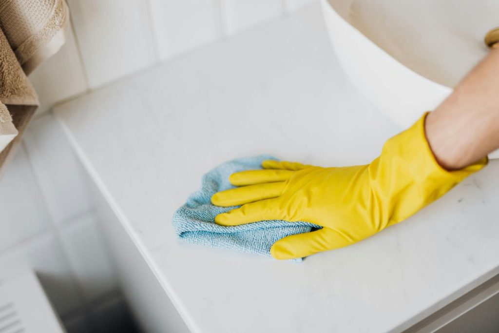 Person cleaning quartz bathroom countertop with microfiber cloth